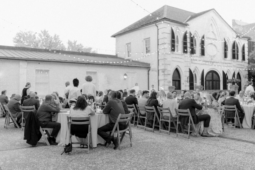 Black and white photo of open air wedding reception dinner at William Aiken House. 
