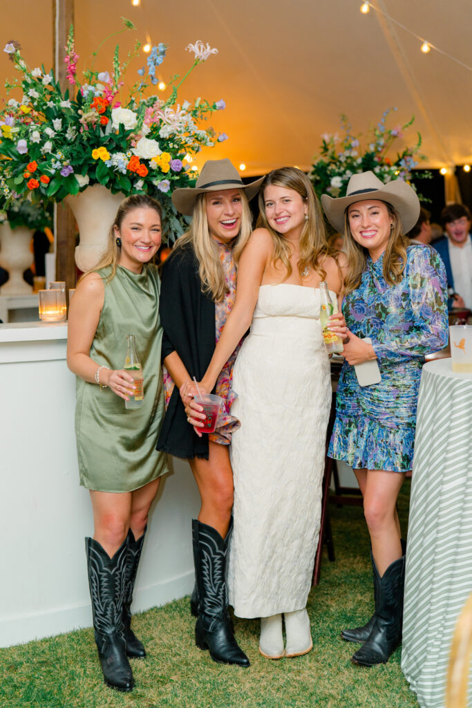 Bride with her best friends from high school at outdoor wedding welcome party on Kiawah Island. Cowboy boots and Stetson hats. 