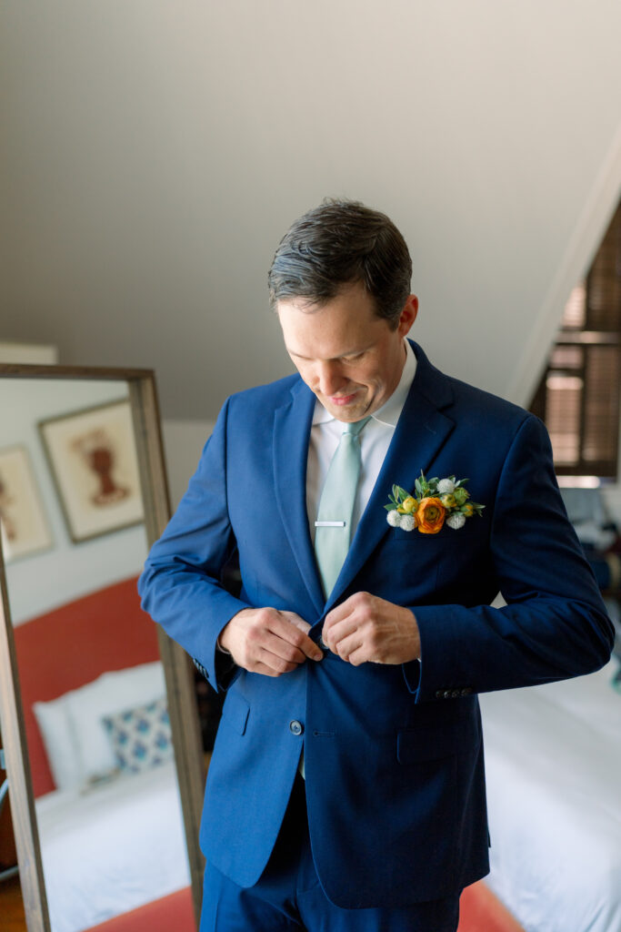 Groom in blue suit and green sea foam tie. Pocket full of flowers instead of boutonniere. 