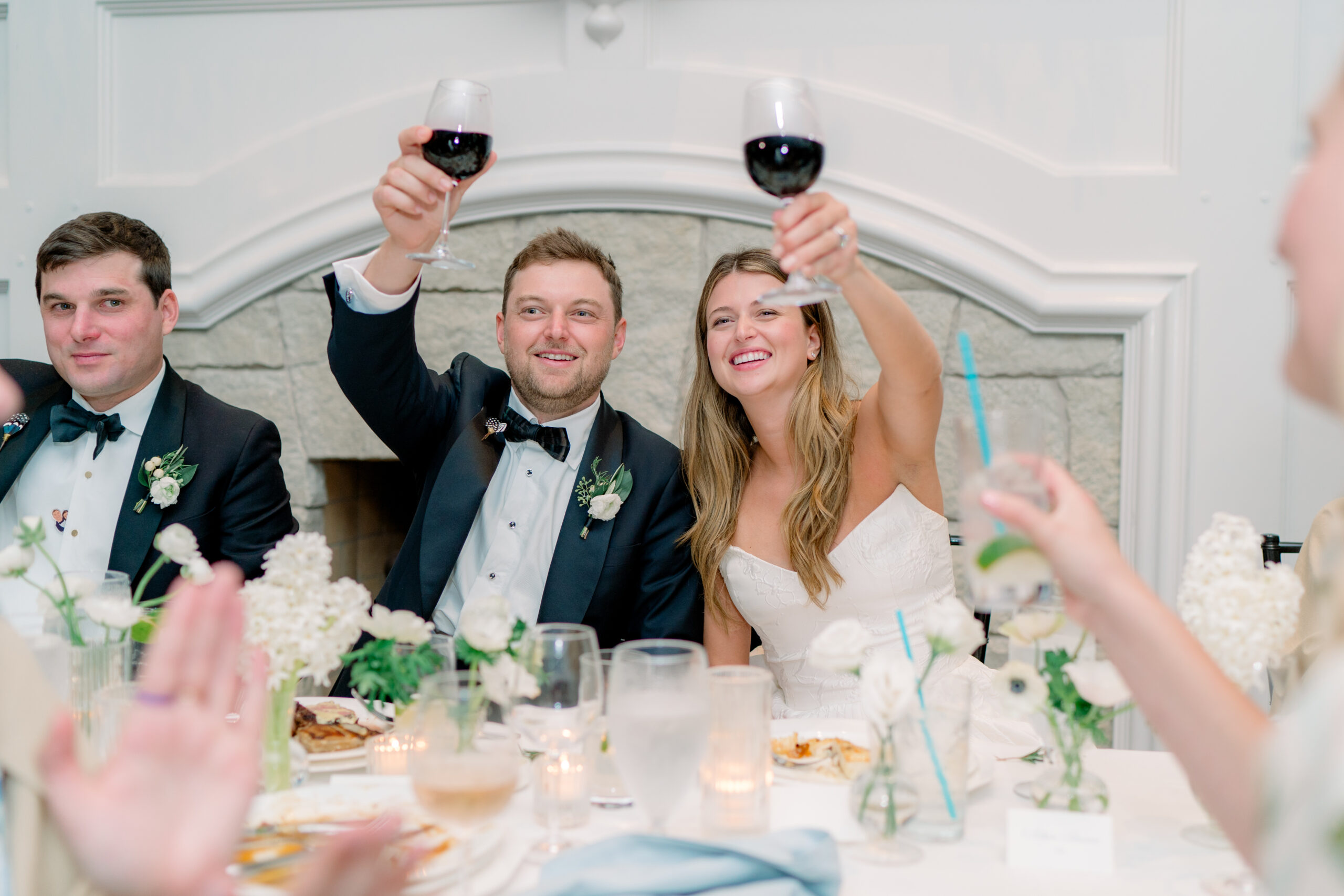 Bride and groom raise a glass during speeches at wedding reception. 