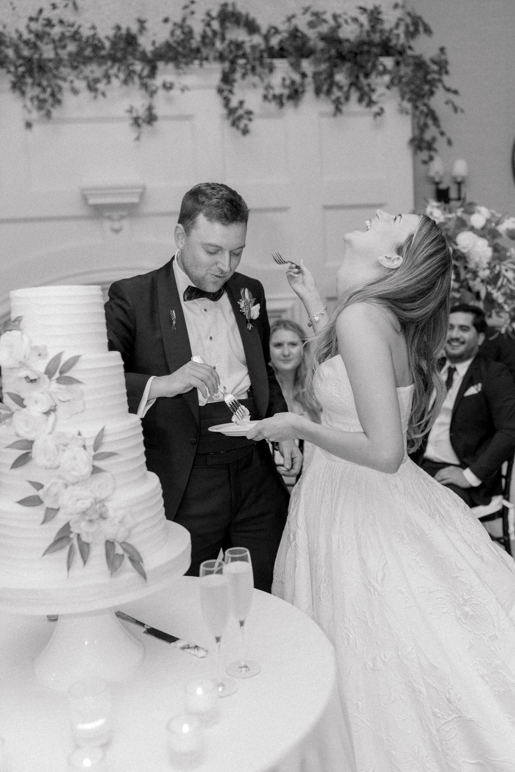 Black and white photo of bride and groom feeding each other cake. 