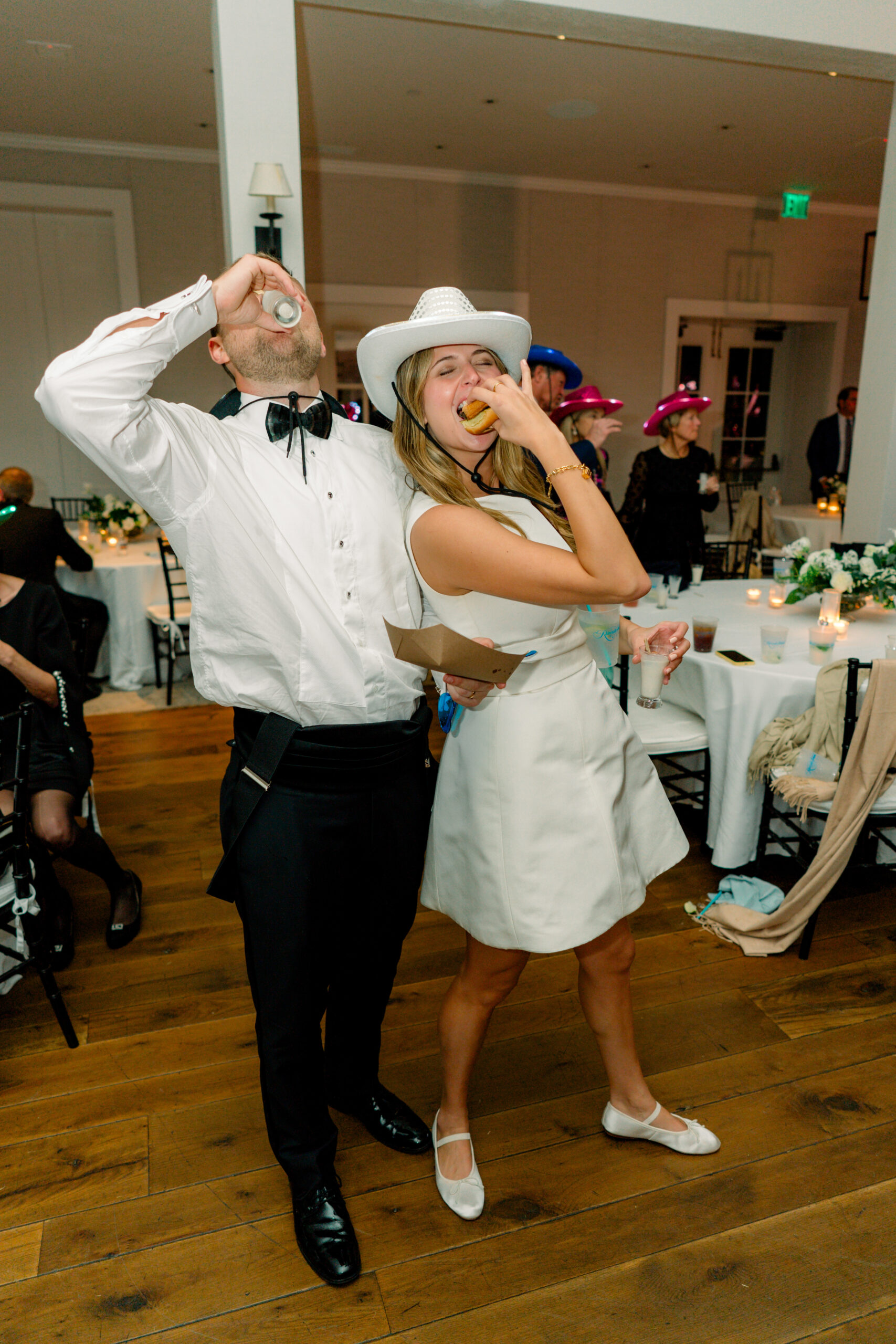 Bride and groom wearing cowboy hats eat late night bites. Milk and cookies and cheeseburgers.