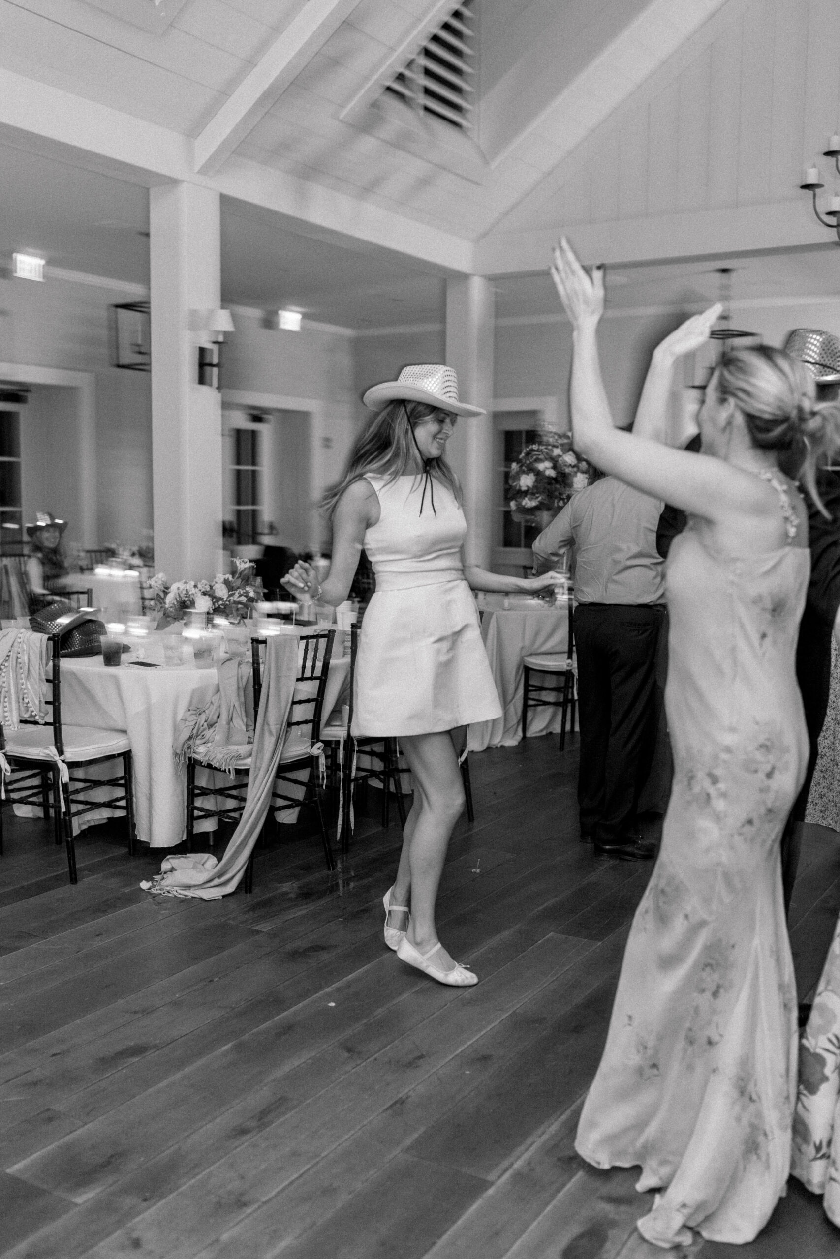 Black and white motion blur photo of bride in second dress, ballet flats, and a stetson hat. 