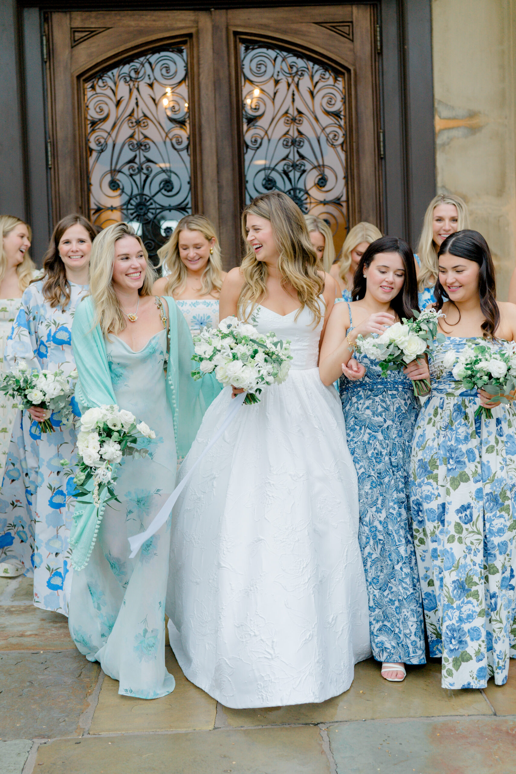 Bride and bridesmaids group photo at Cassique. Mix-matched blue and green floral bridesmaid dresses. 