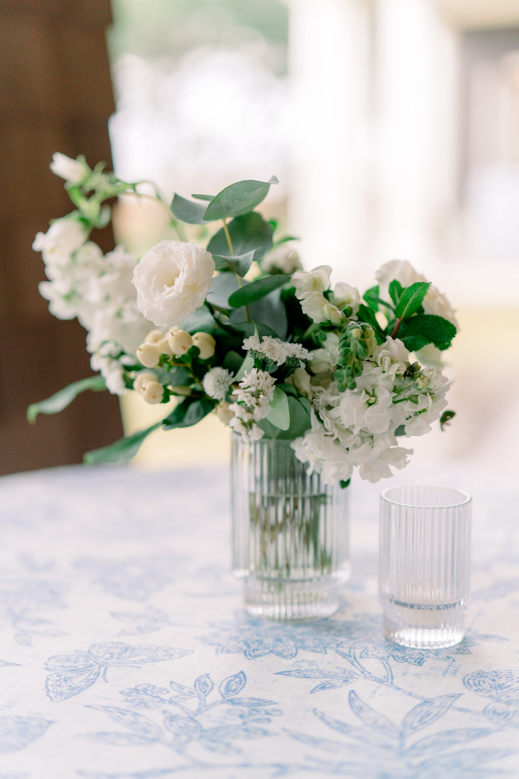 White and green cocktail hour high top flowers with blue and white floral table cloth. Kiawah River Course fall wedding. 