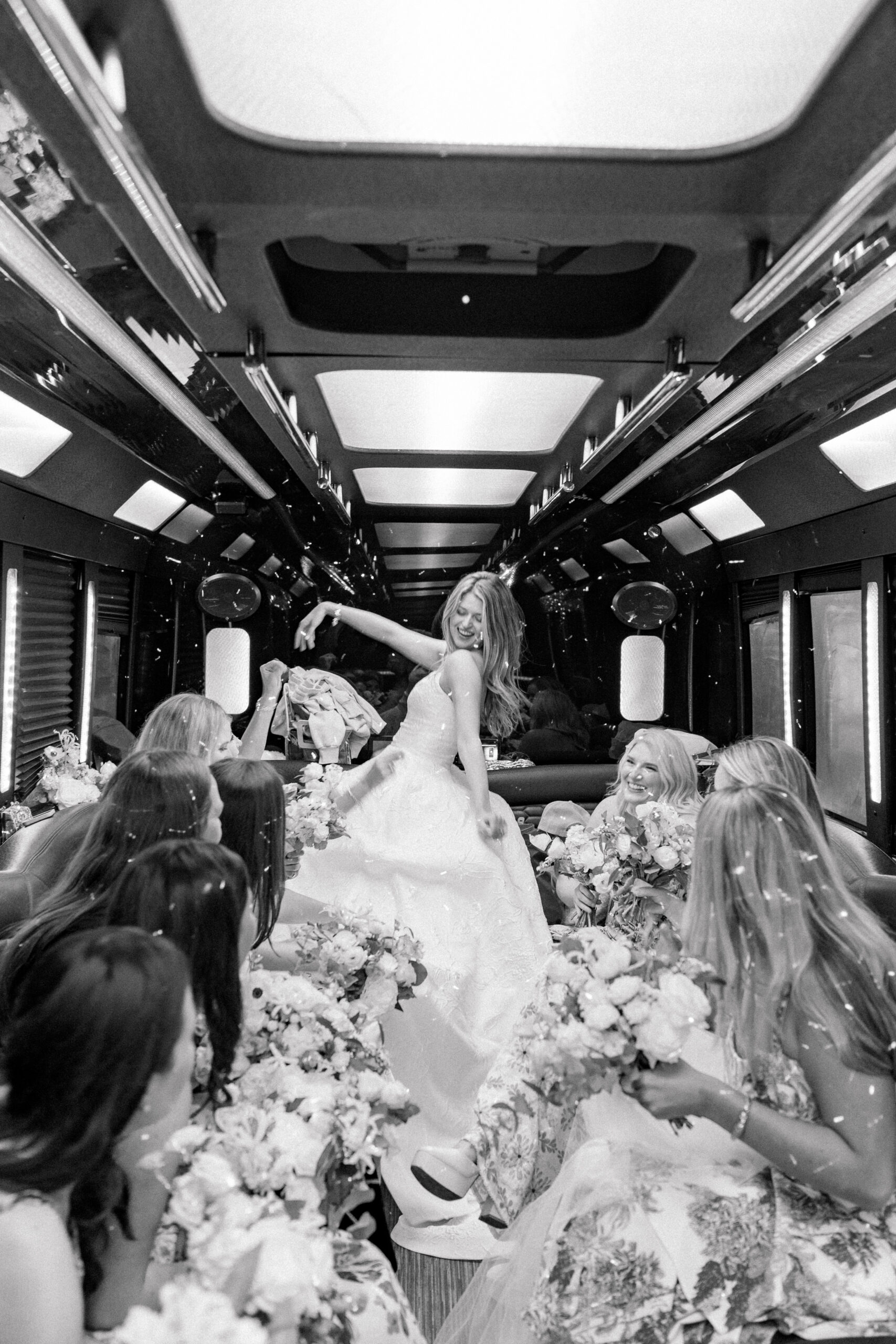 Bride arrives to the wedding ceremony on a party bus. Black and white candid photo of bride with her bridesmaids. 
