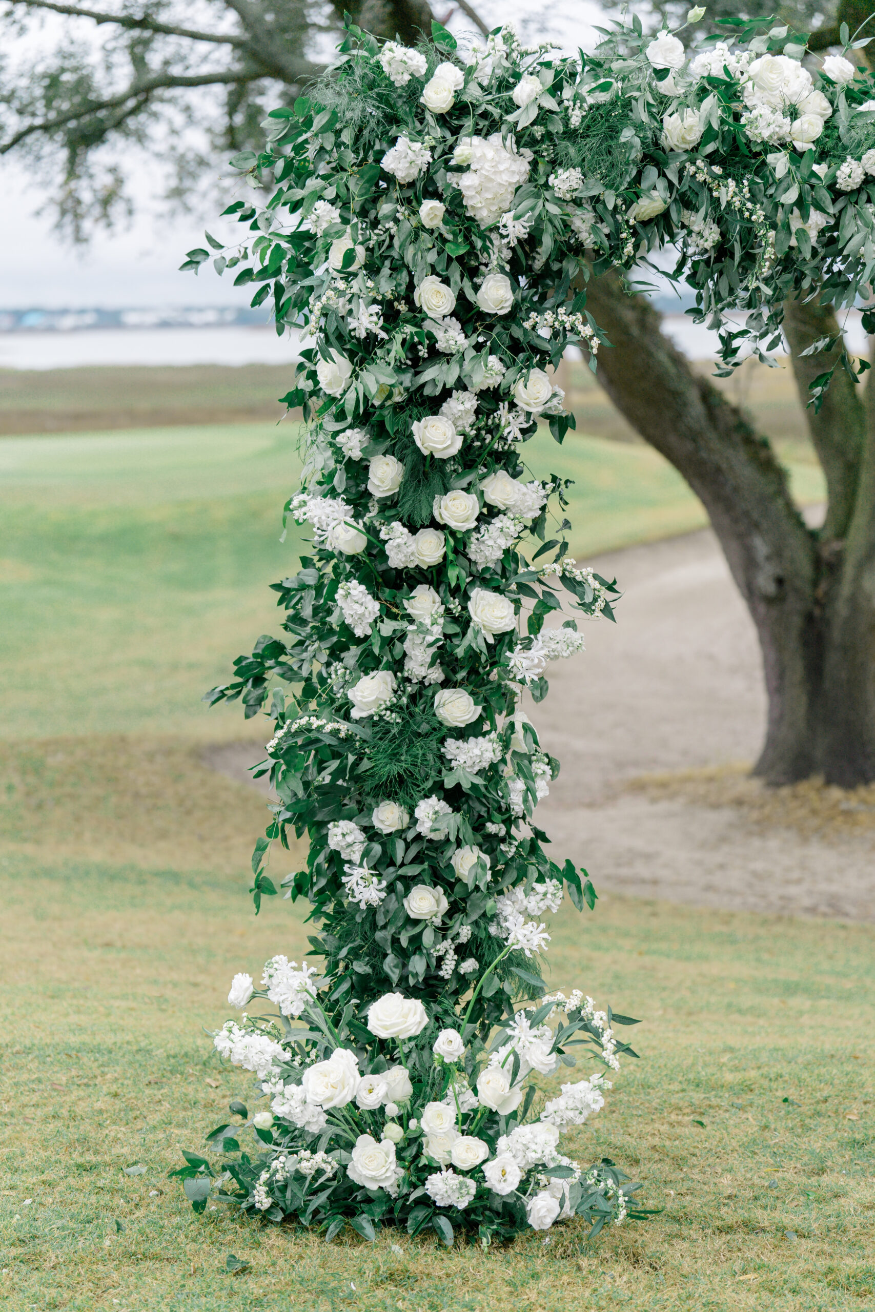 White and green flower arch. Waterfront sunset wedding reception at Kiawah River Course. 