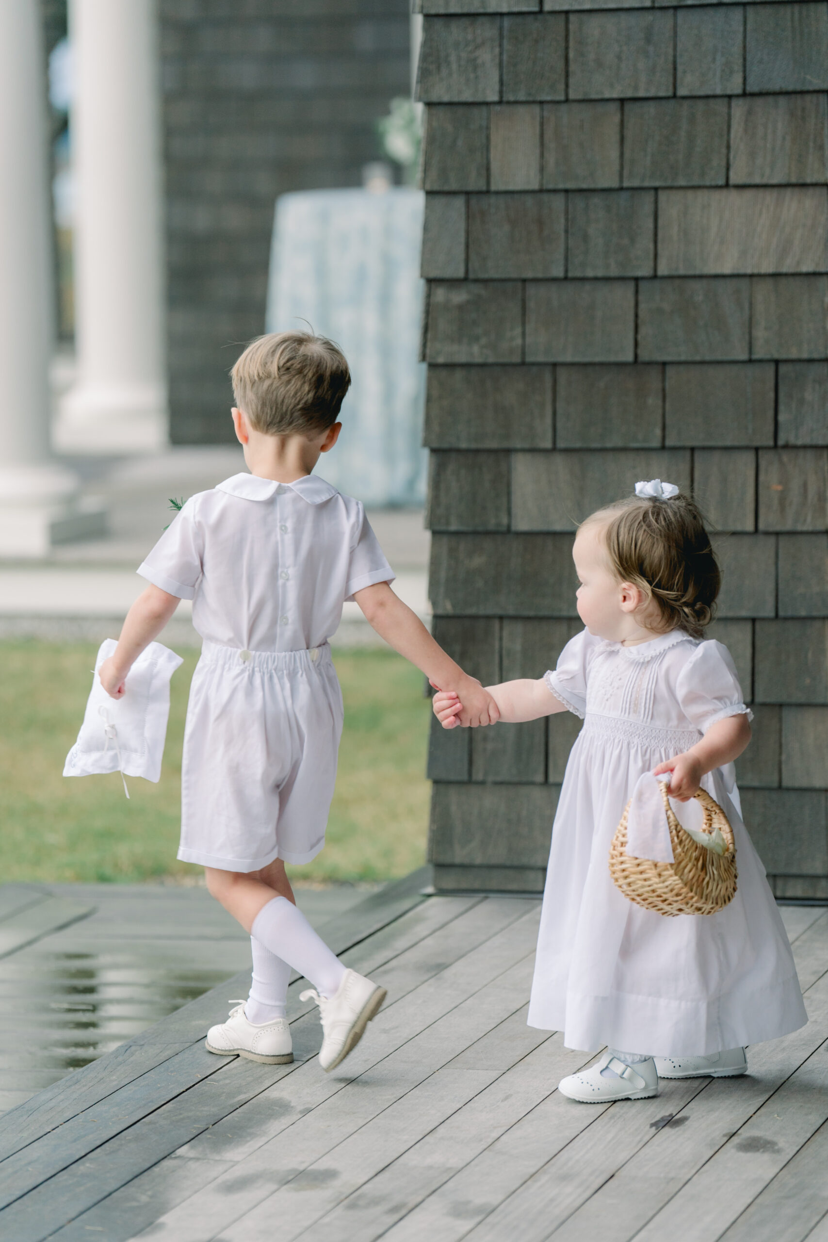 Ring bearer helps very young flower girl to outdoor waterfront wedding ceremony on Kiawah Island.