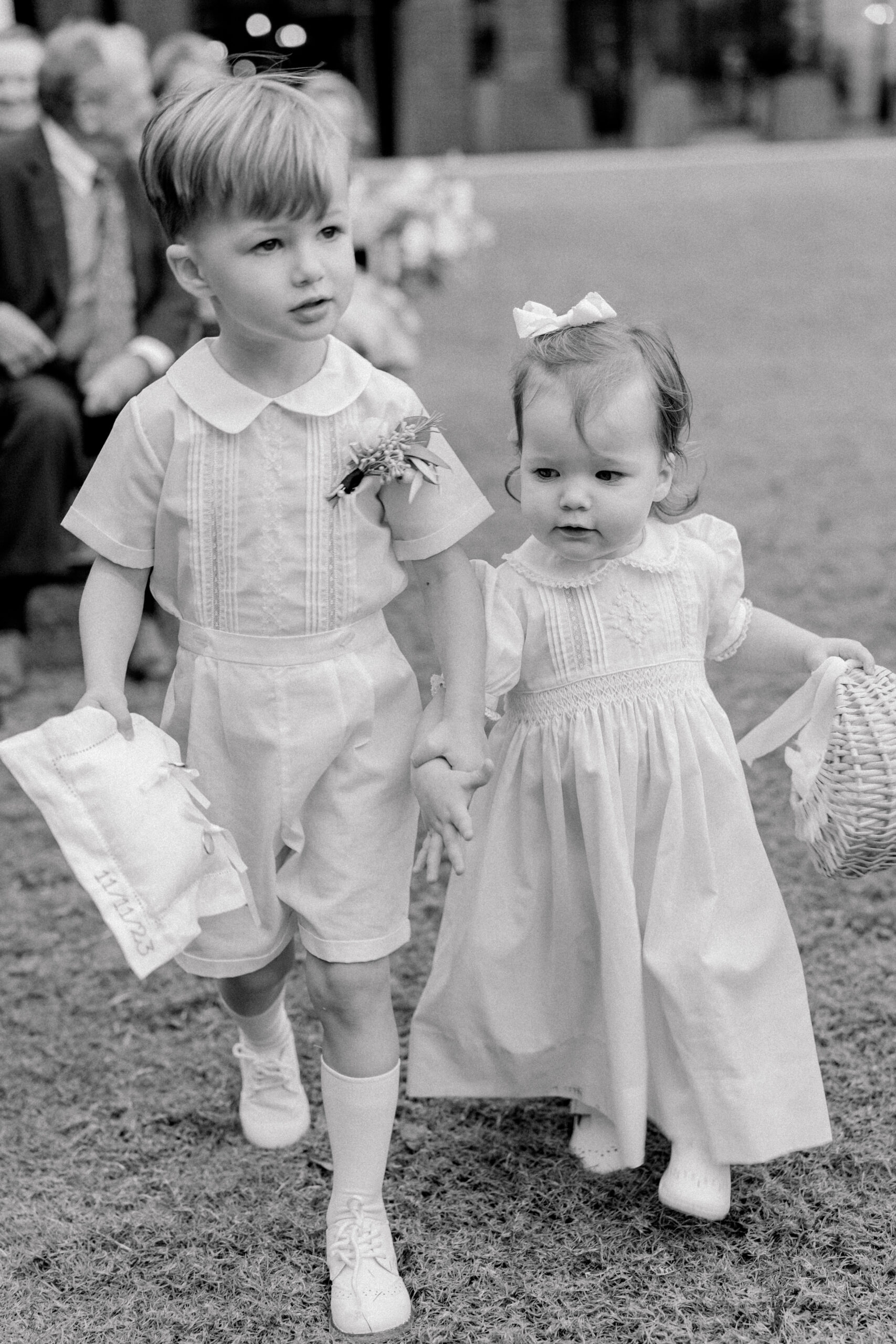 Ring bearer and flower girl hold hands and walk up the aisle. 
