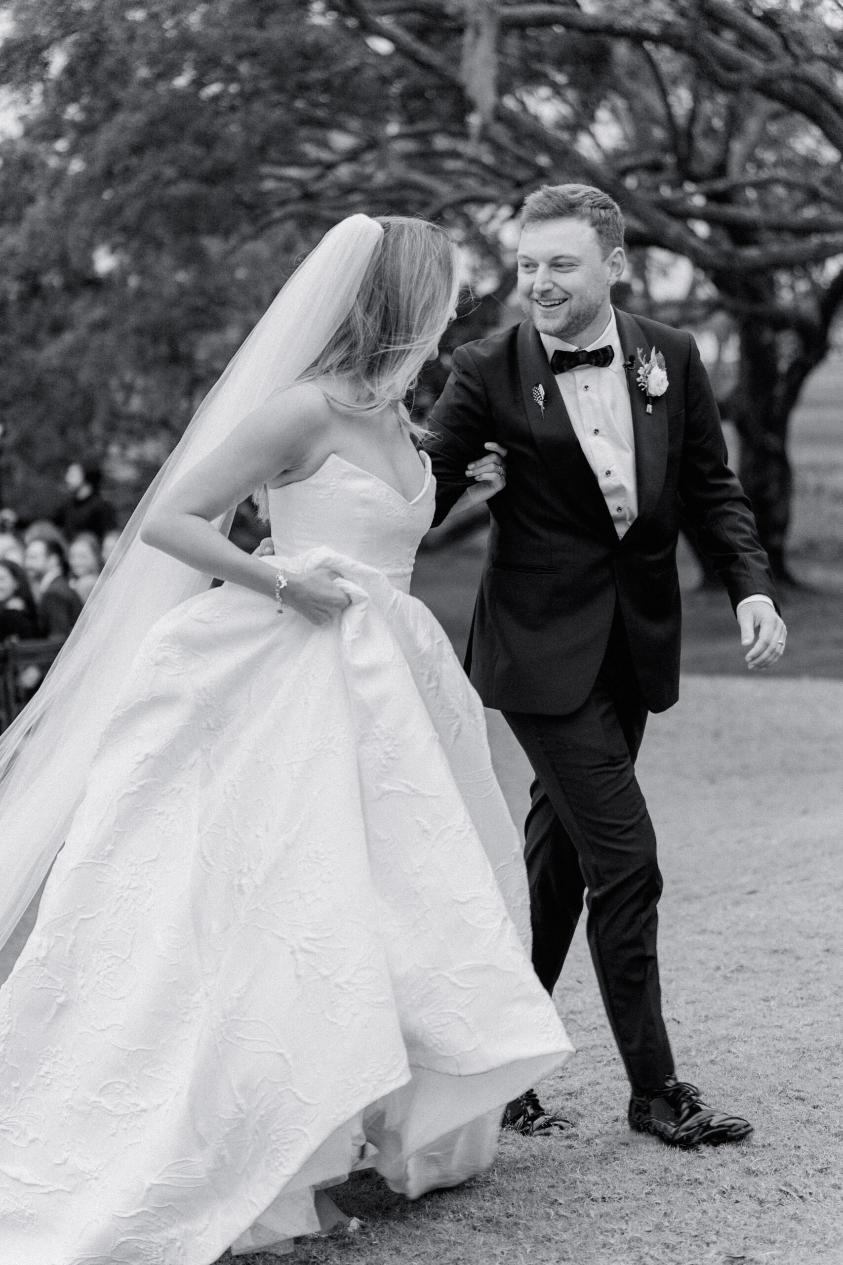 Bride and groom smile at each other after wedding ceremony. Black and white wedding photo. 