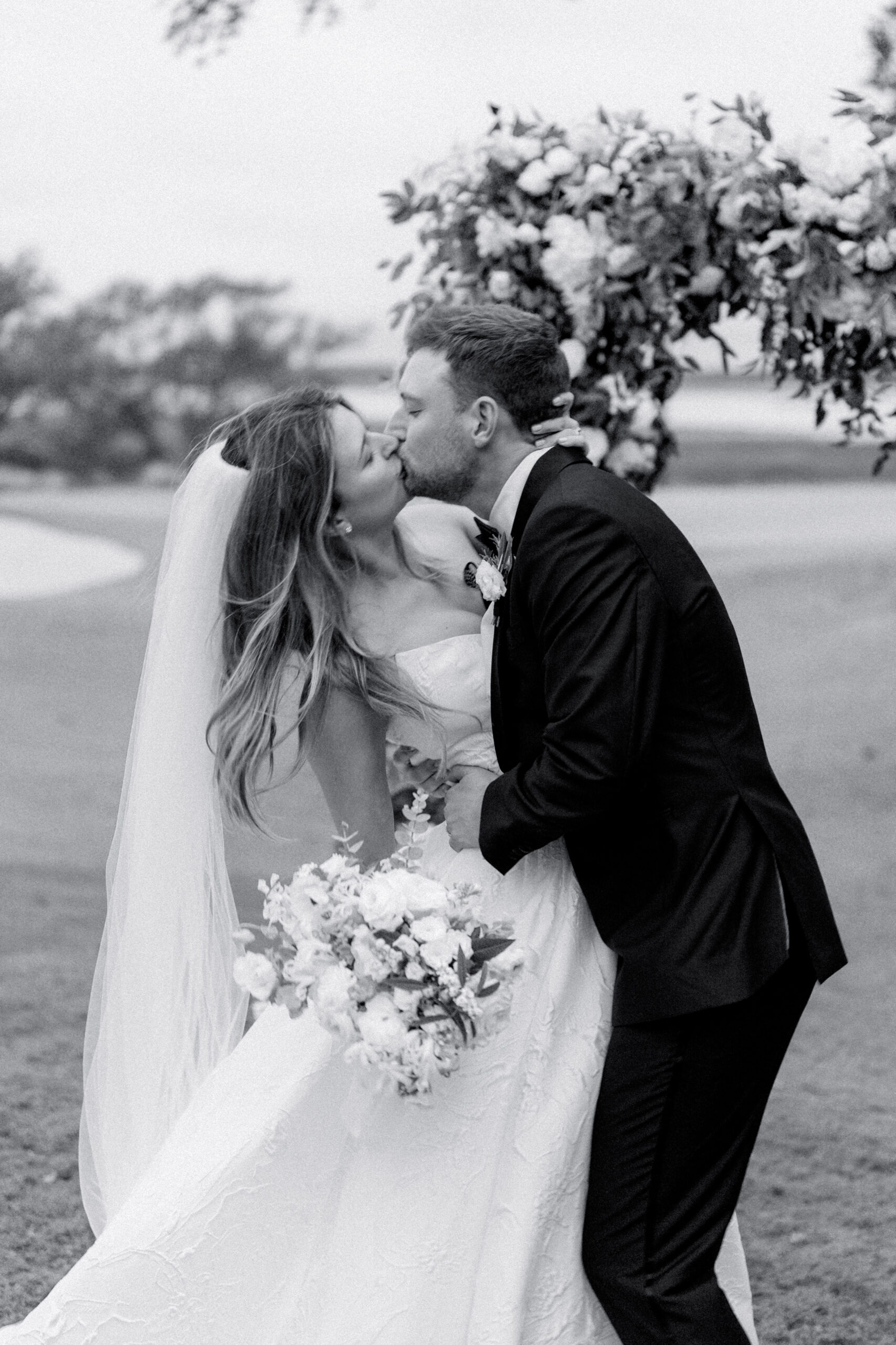 Black and white photo of bride and groom kissing.