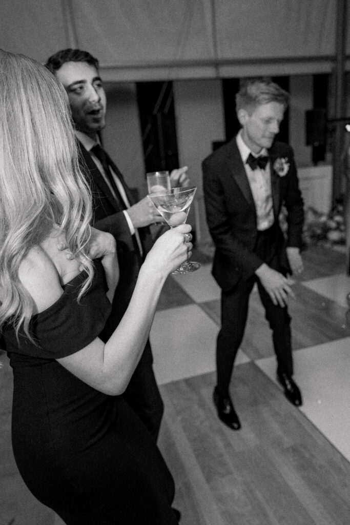 black and white photo of wedding guest holding martini on the dance floor. 