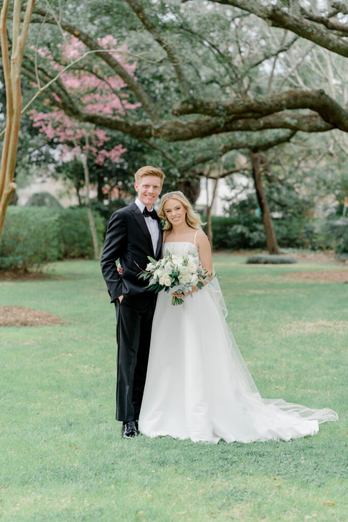 Bride and groom portrait at Lowndes Grove with pink tree blooming in the background. Charleston photographer.