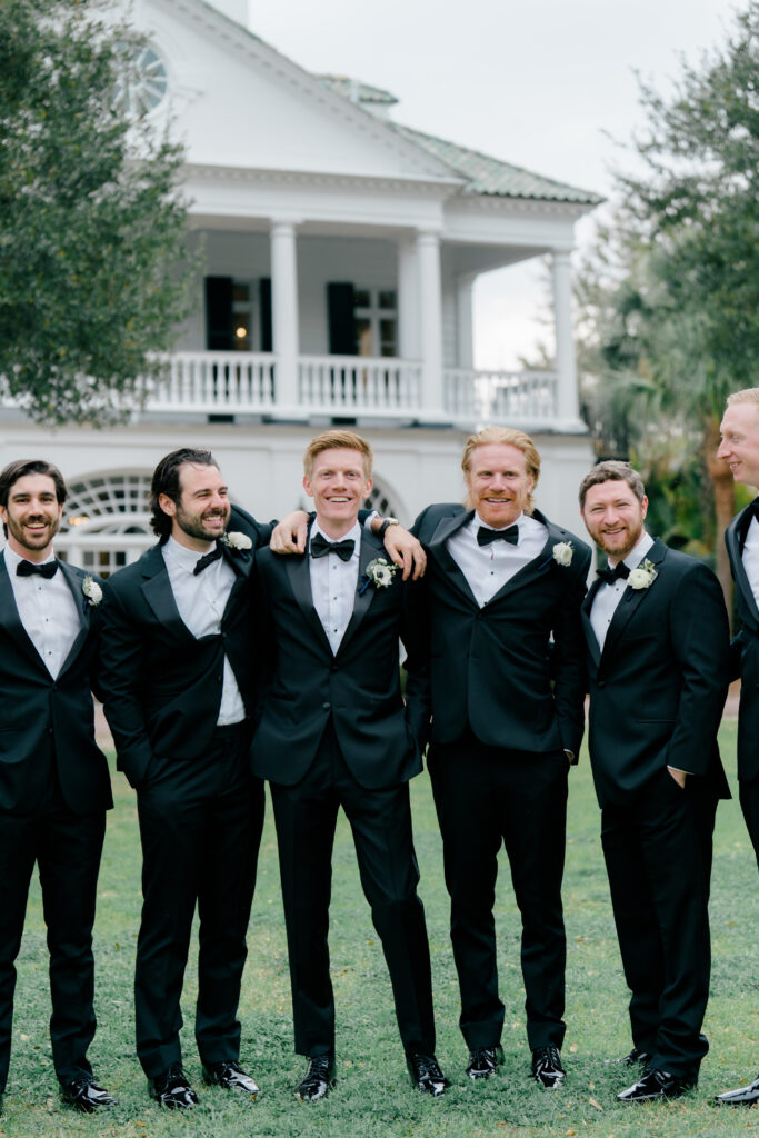 Groom and groomsmen in black tuxedos at Lowndes Grove. 