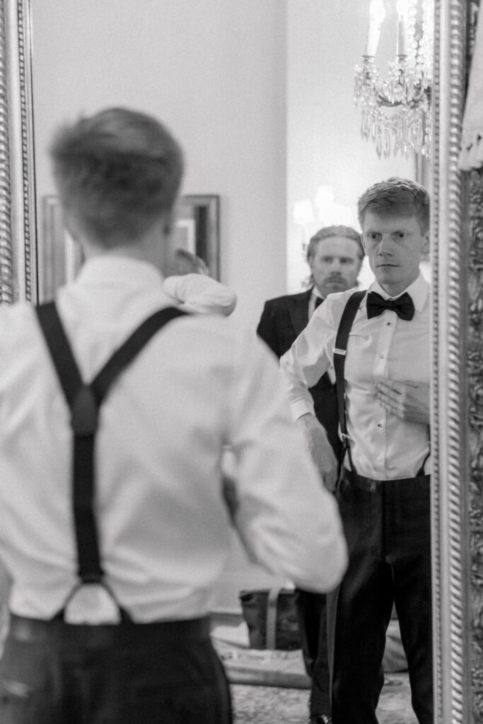 Black and white photo of groom getting dressed