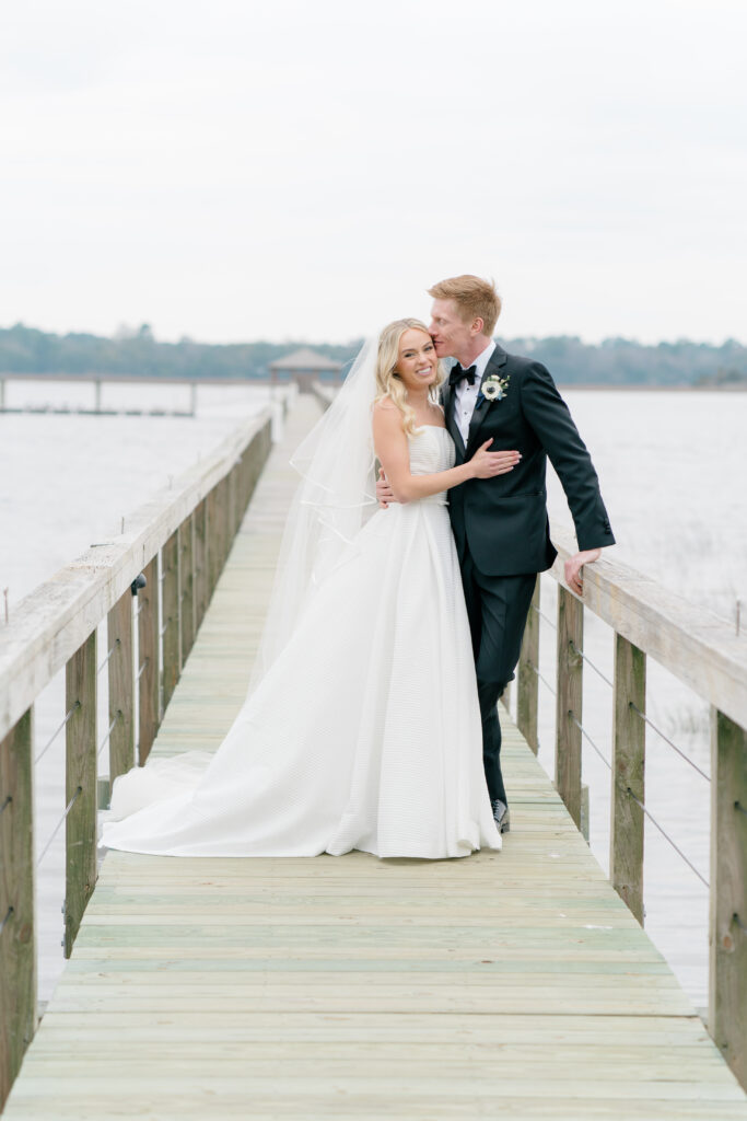 Groom kissing brides forehead on the dock at Lowndes Grove. Waterfront wedding venue Charleston, SC. 