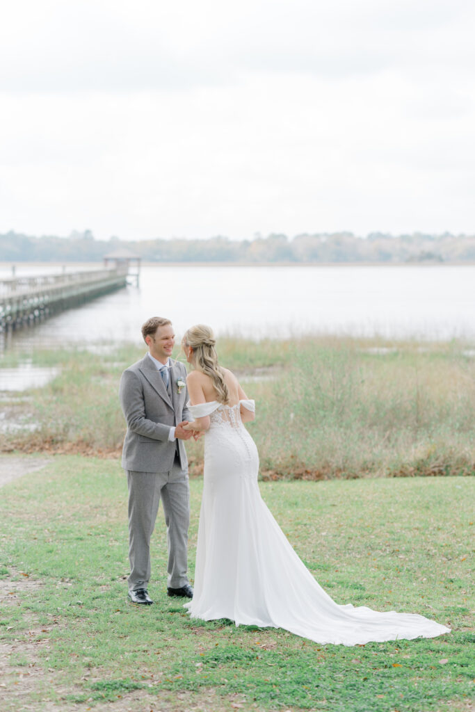 Groom smiles at the bride with Lowndes Grove dock in the background. 