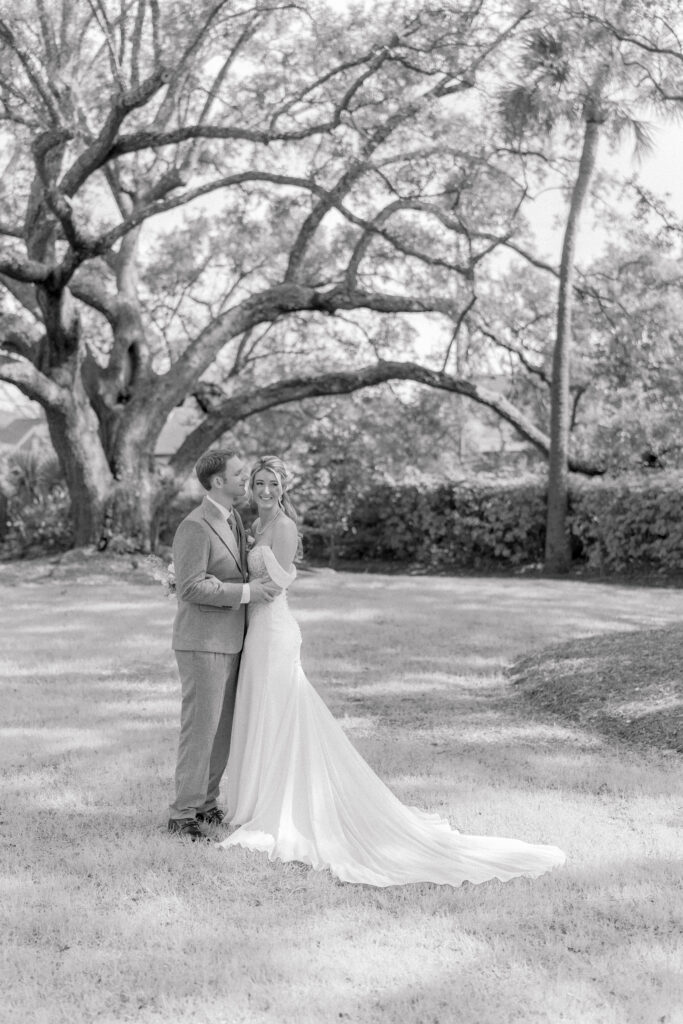 Black and white portrait of bride and groom with big oak tree in the background. 