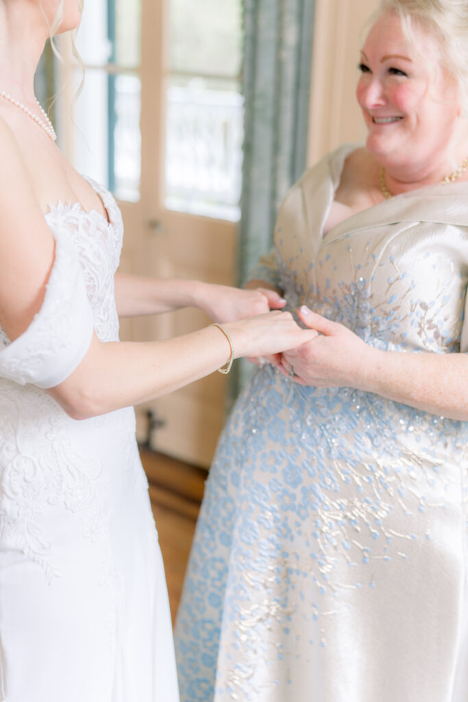 Bride holds her moms hand.