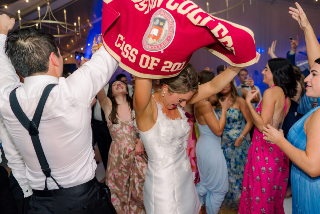 Bride hits the dance floor with college flag after big group photo. Boston College wedding.