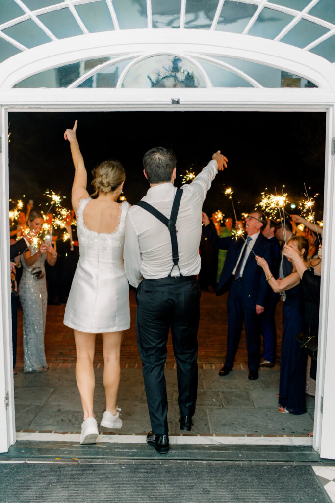 Bride and groom walk out the door during sparkler exit at Lowndes Grove. 