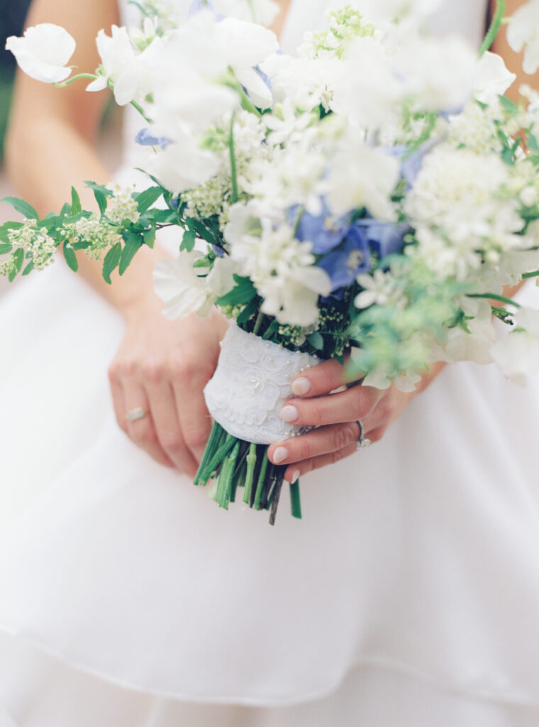 White and green wedding bouquet with touches of blue. Brides mom's wedding dress wrapped around her flowers. 