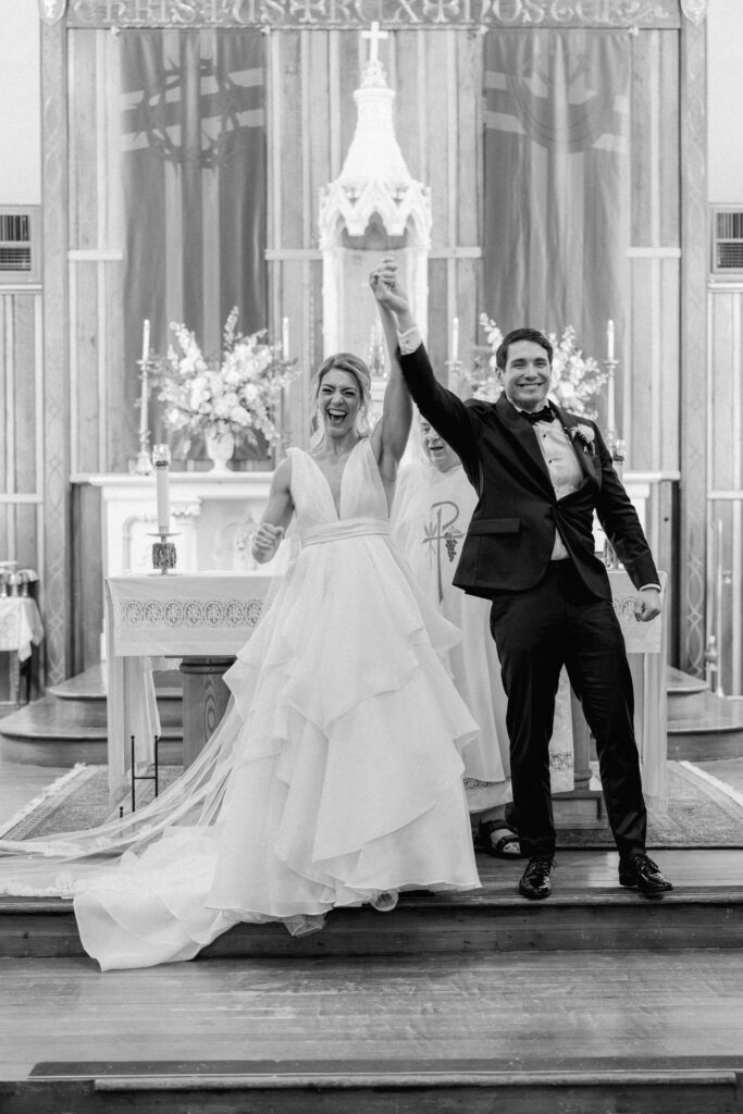 Bride and groom celebrate after first kiss at Charleston spring church wedding ceremony. Black and white wedding photo.