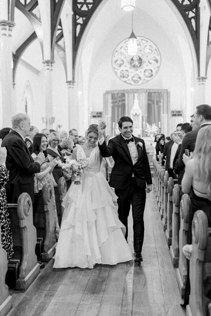 Black and white photo of bride and groom walking down the aisle. Church ceremony at Charleston wedding.