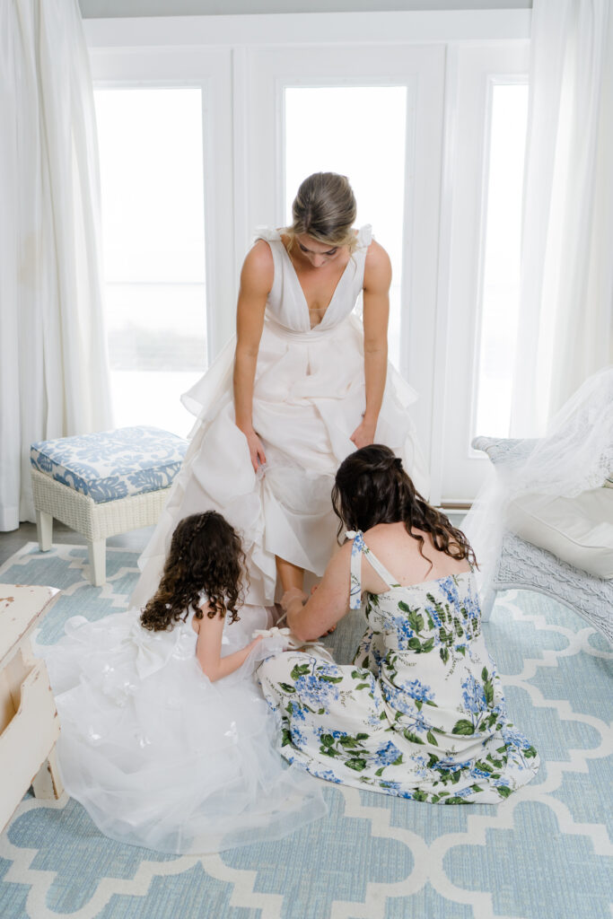 Bride's sister and niece helps her put on wedding day heels. 