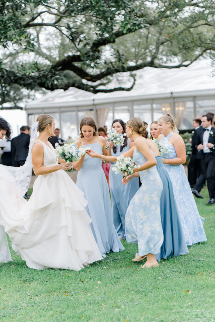 Bridesmaids in blue check out brides wedding band. 