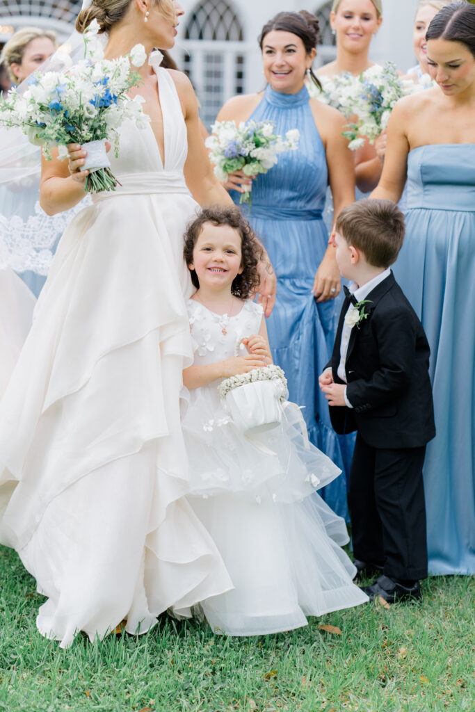 Candid moment of flower girl smiling and looking at camera during full bridal party portraits. 