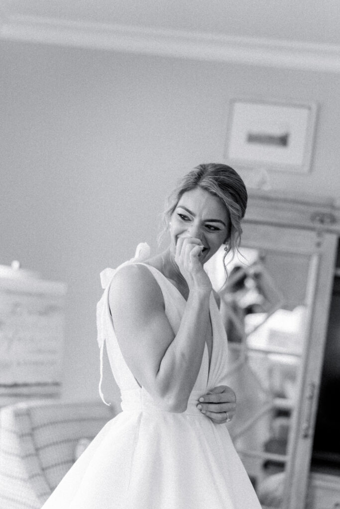 Candid black and white photo of bride laughing before first look with her bridesmaids.
