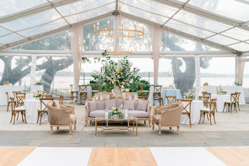 Clear tent at Lowndes Grove wedding reception. Big floral centerpiece with couches and tables. Waterfront wedding reception. 