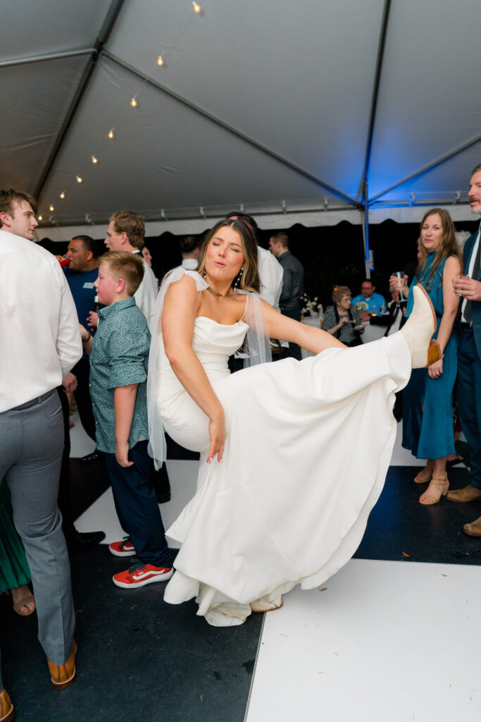 Bride plays air guitar with her leg on the dance floor. Fun Charleston bride. 