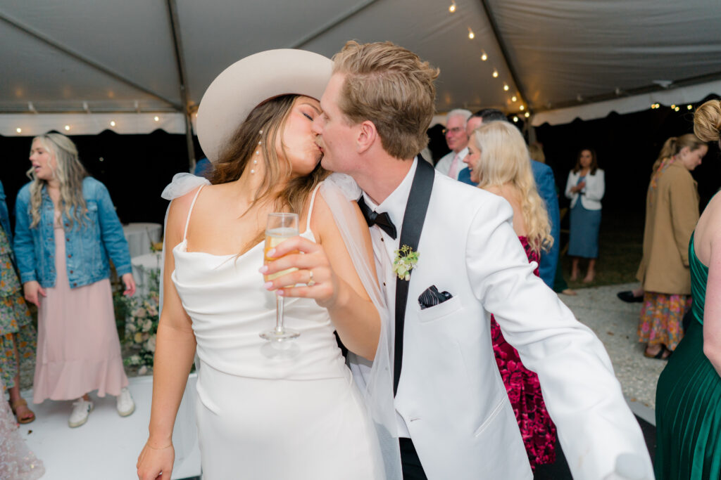 Flash photo of bride and groom kissing at Charleston wedding reception. Bride wearing custom cowboy hat. 