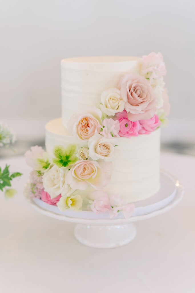 Two-tier wedding cake with pink flowers and a touch of green. 