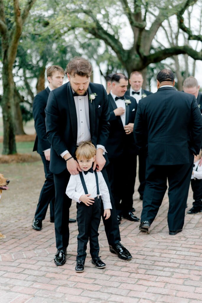 Ring bearer gets his collar fixed by his day. 