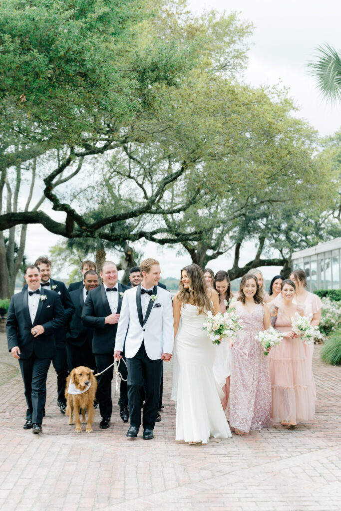 Bride and groom walking with the bridal party and their dog. Golden retriever. 