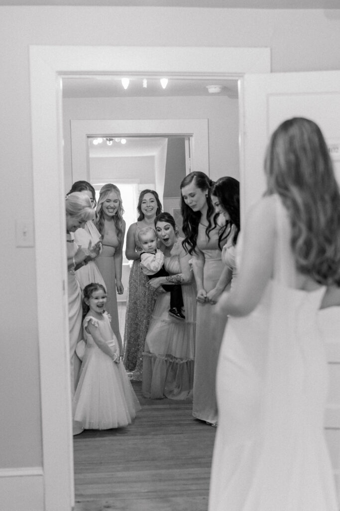Bride first look with bridesmaids and flower girl. Black and white wedding photo. 