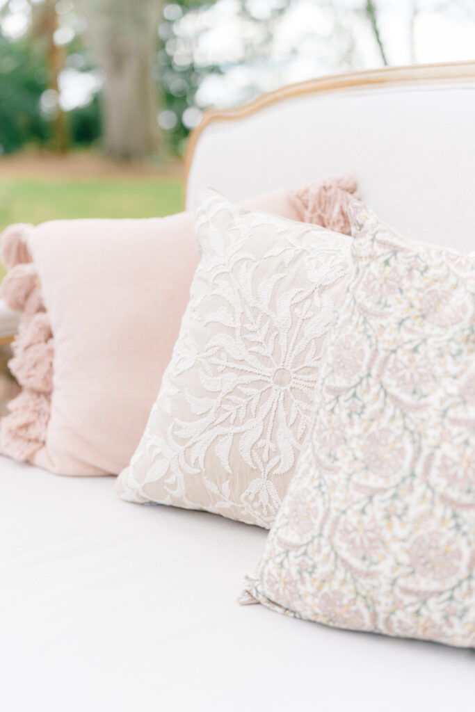 Textures and patterns on white and pale pink couch pillows. 
