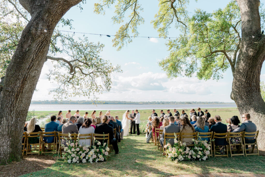 Waterfront wedding ceremony under live oak trees. River House at Lowndes Grove. 