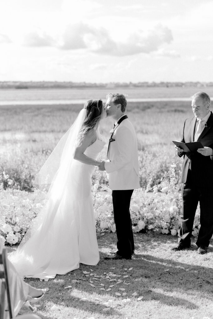 Black and white photo of wedding ceremony first kiss on gorgeous spring day in Charleston, SC.