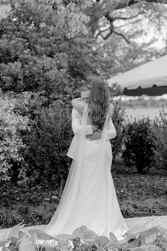 Black and white wedding photo. Bride and groom hug after first look. 