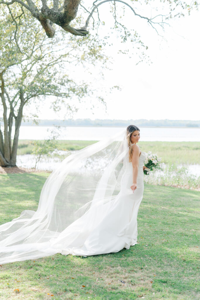 Bride holds onto her dress with veil blowing in the wind. Lowndes Grove bridal portrait.