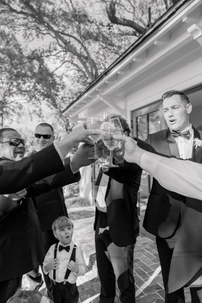 Groomsmen toast to the bride and groom with ring bearer cheering.