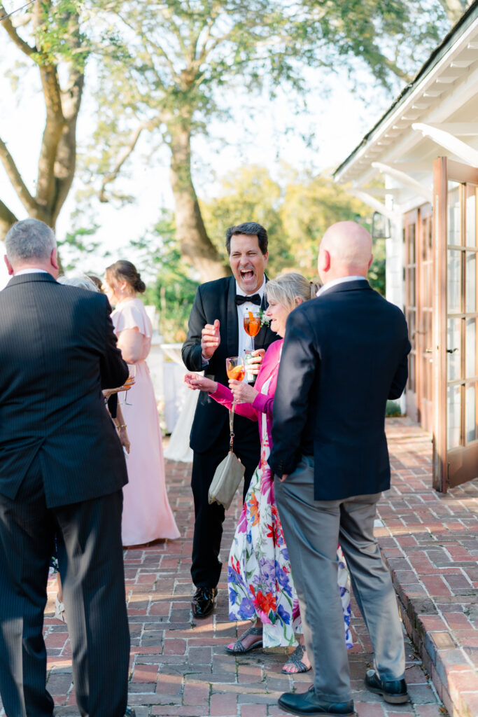 Candid of father of the bride laughing at cocktail hour.