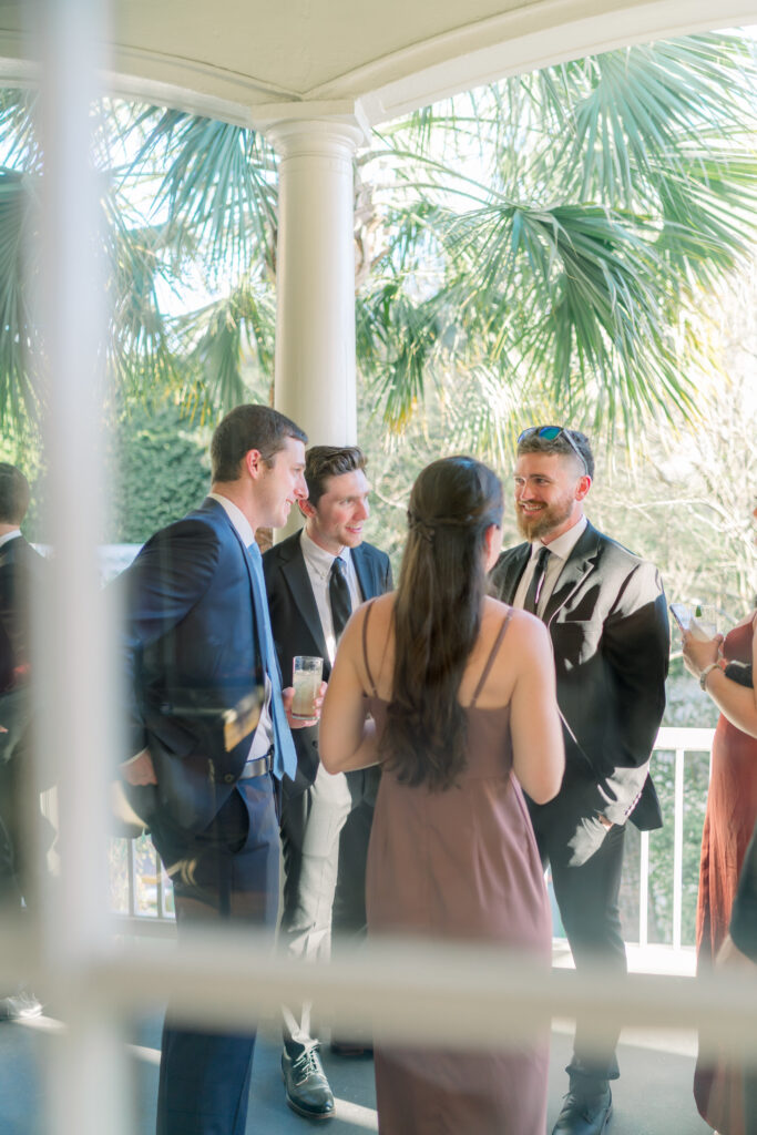 Wedding guests mingle on the porch at William Aiken House during cocktail hour. 