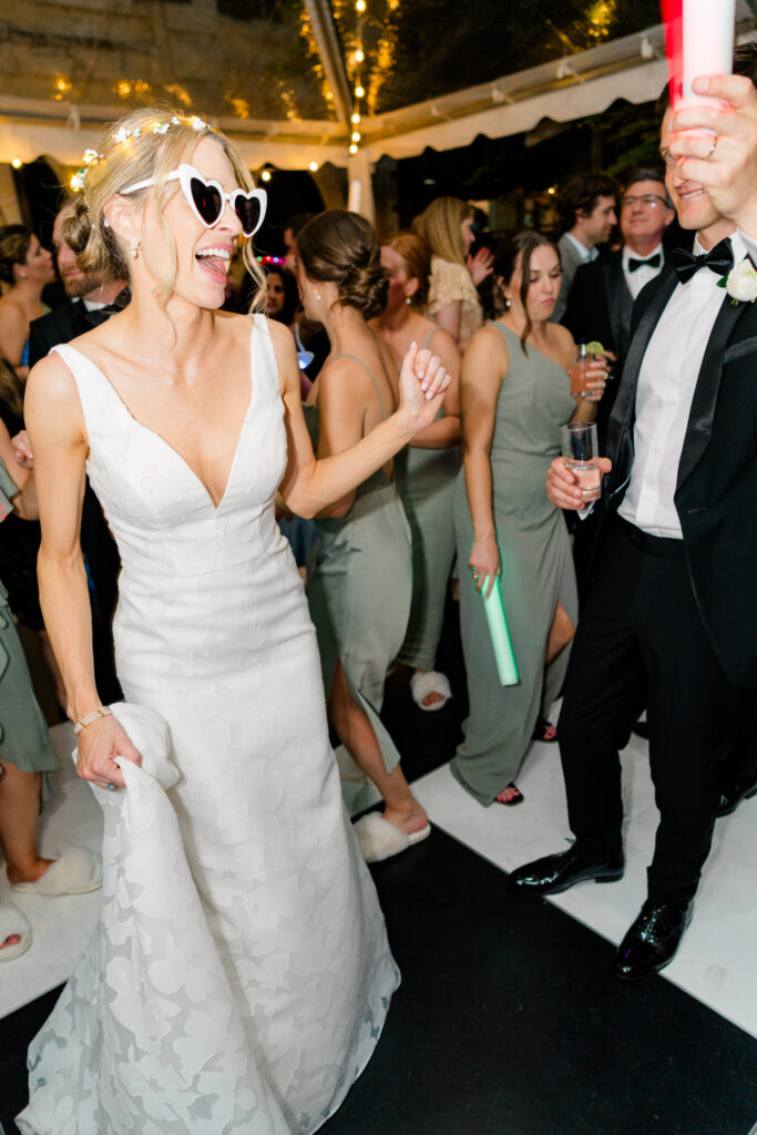 Bride wears fun sunglasses on the dance floor. Wedding flash photography. 