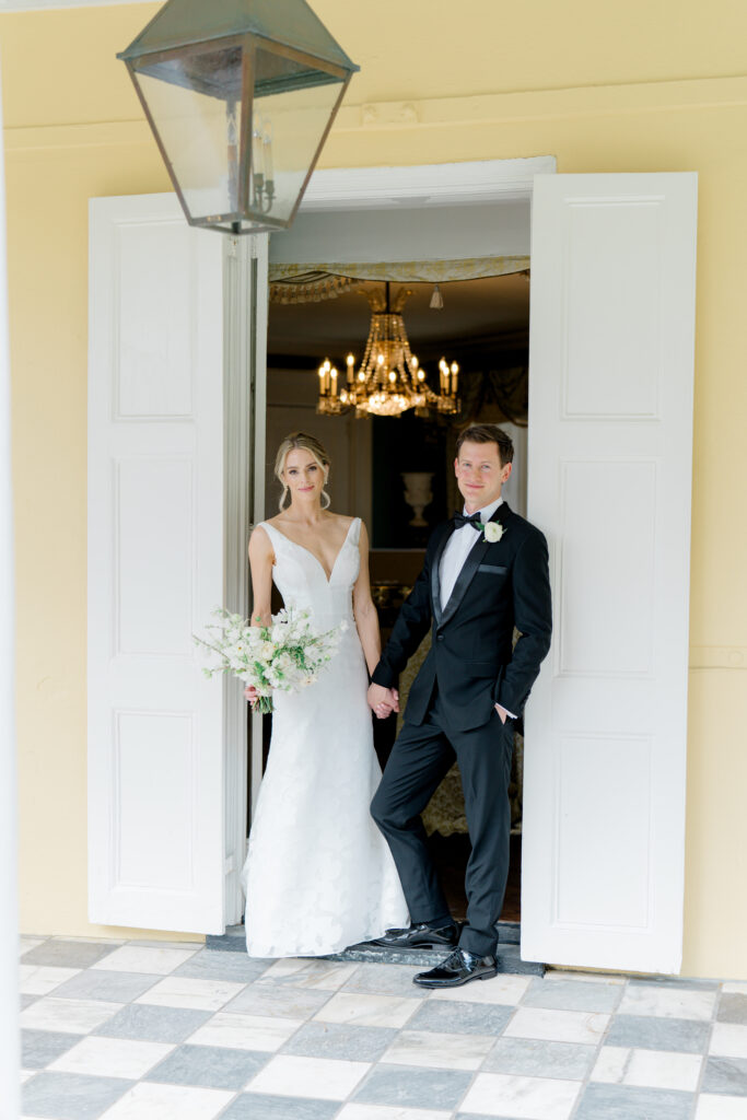 Bride and groom holding hands in the doorway at William Aiken House. 