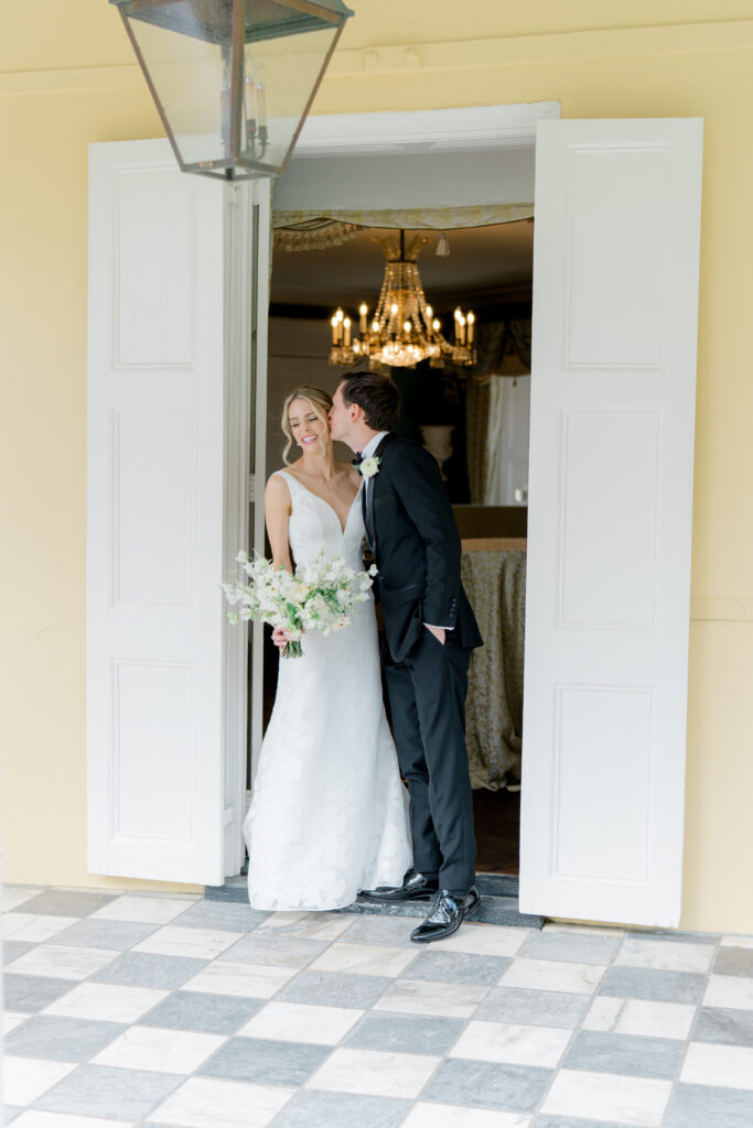 Groom kisses bride's cheek in cute moment during spring wedding in Charleston. 